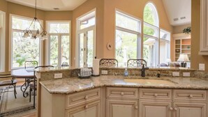A kitchen with large windows, granite countertops, and a dining area with a table and chairs. - 4 Minute Walk to Beach!  Private Pool With Pool Heater.*  Back Deck w/ Lagoon & Golf Course Views! (Hilton Head Island)
