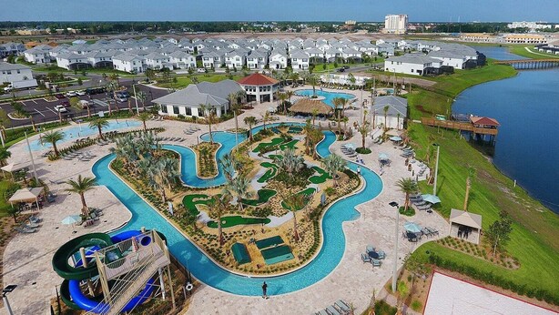 A resort with a large pool area, a water slide, and a view of the surrounding buildings. - Lovely Family Home - 8 Min to Disney! (Kissimmee)