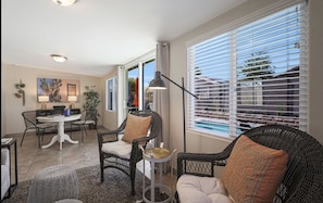 Relax in this open-plan living area with a dining set and seating arrangements, featuring a dining table, side table, and wicker chairs.