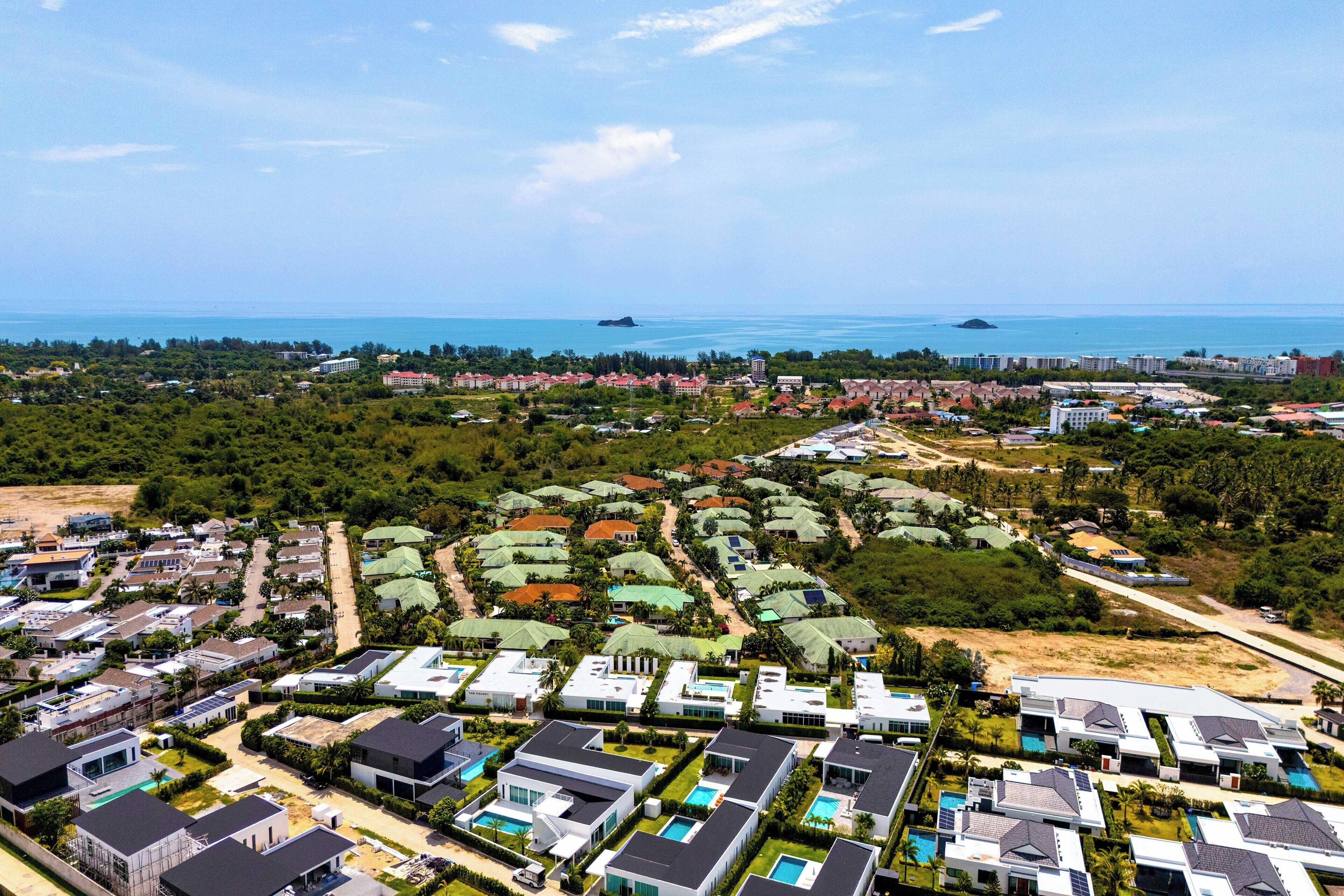 Vista aérea de una zona residencial costera con casas modernas, una playa y una vista despejada del mar.