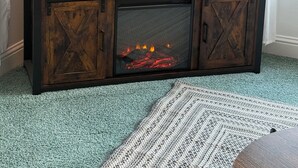 Un téléviseur à écran plat posé sur un meuble télé en bois, avec une cheminée en dessous.