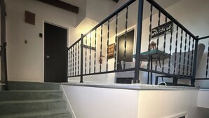 Un escalier avec une rampe sombre menant à un palier.