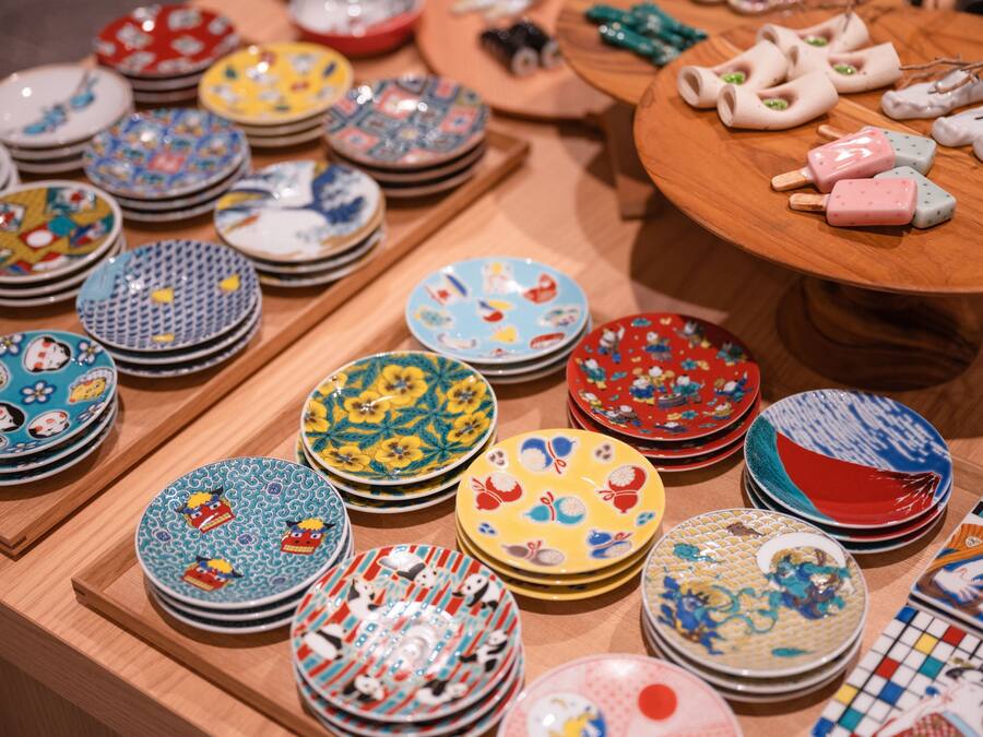 A variety of colorful plates and bowls arranged on wooden shelves and a table.