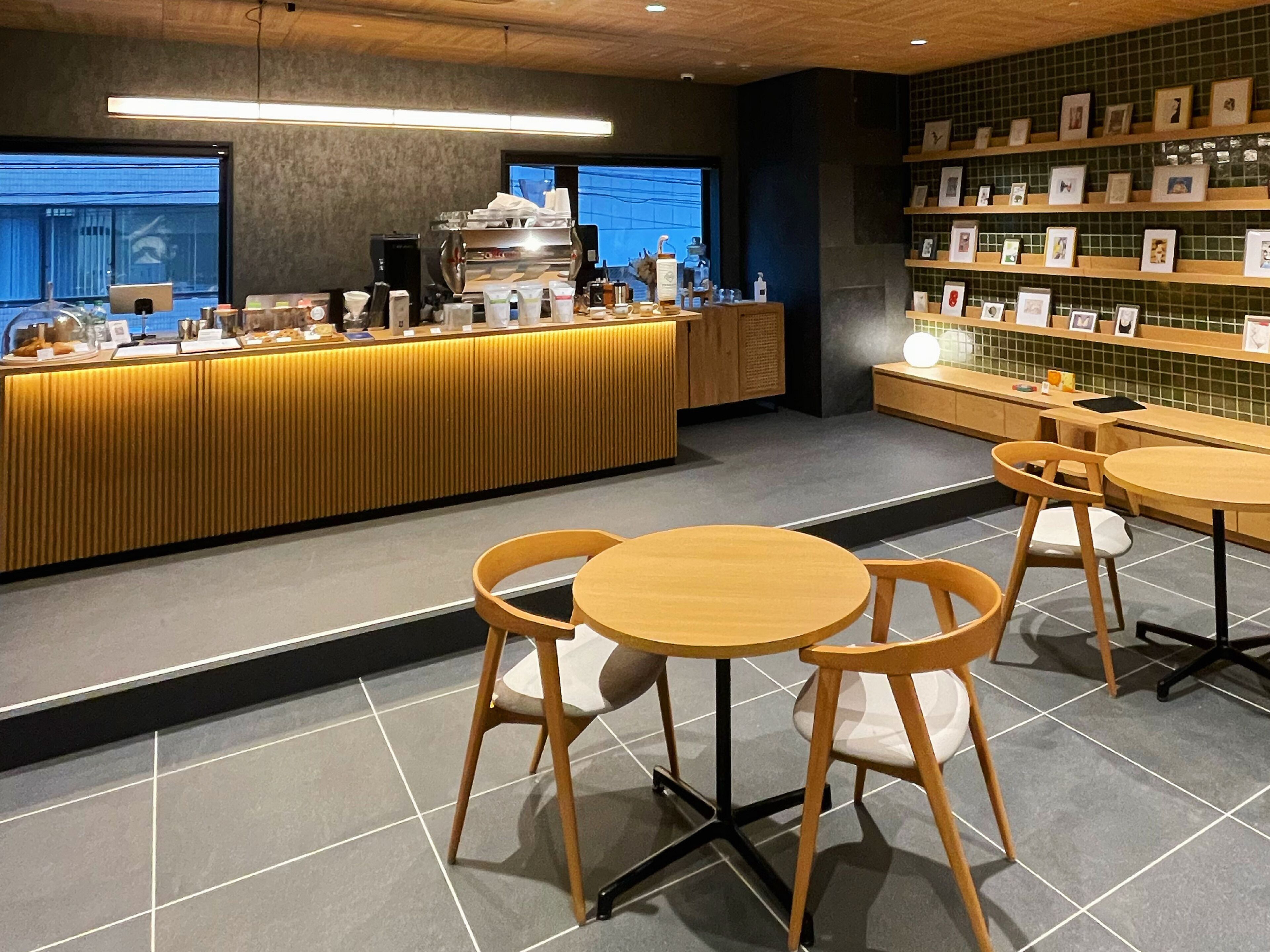A modern cafe interior with a counter, seating area, and framed pictures on the wall.