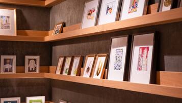 A gallery wall with framed artworks on wooden shelves.