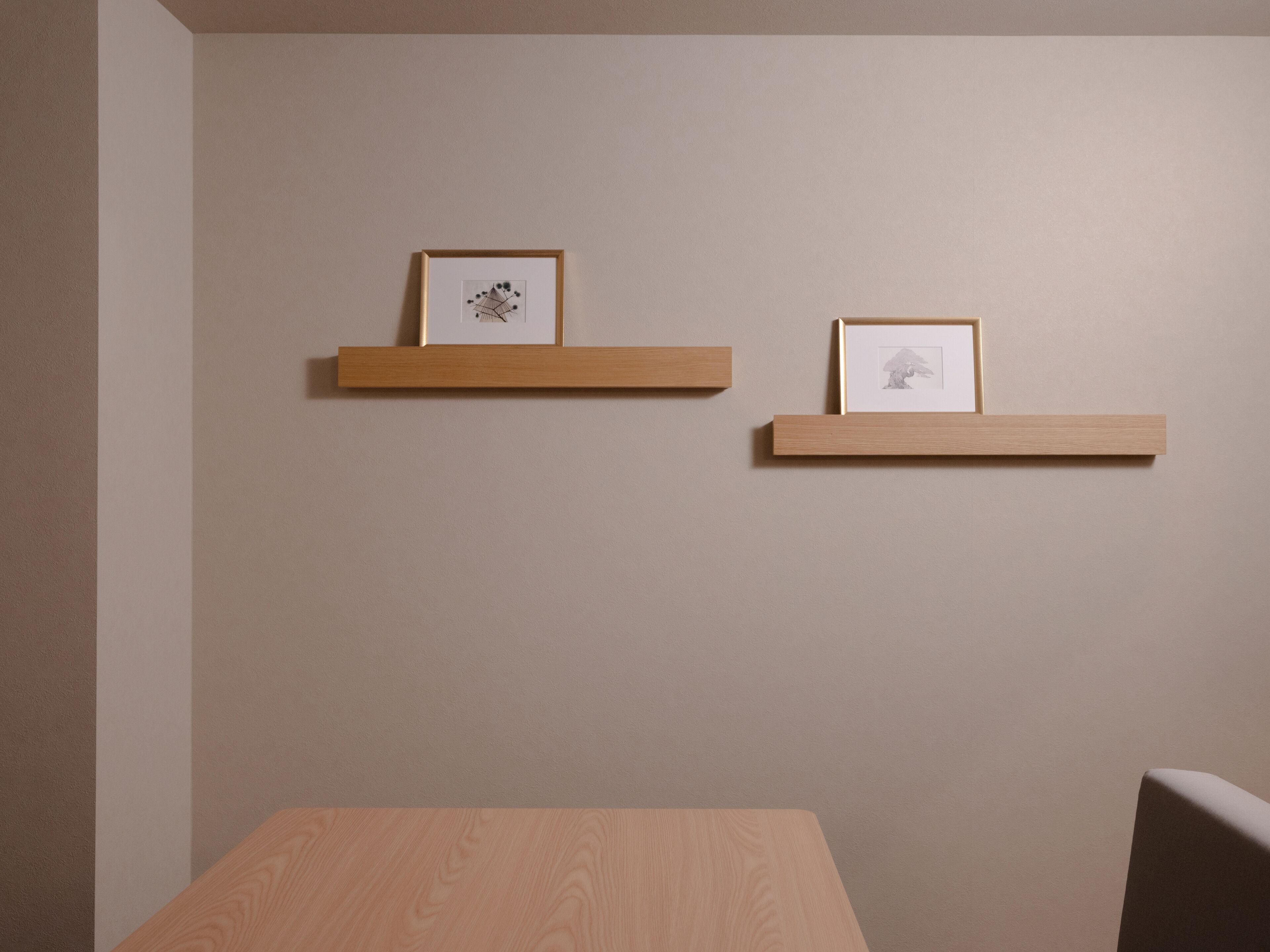 A room with two wooden shelves mounted on the wall, each holding a framed picture.