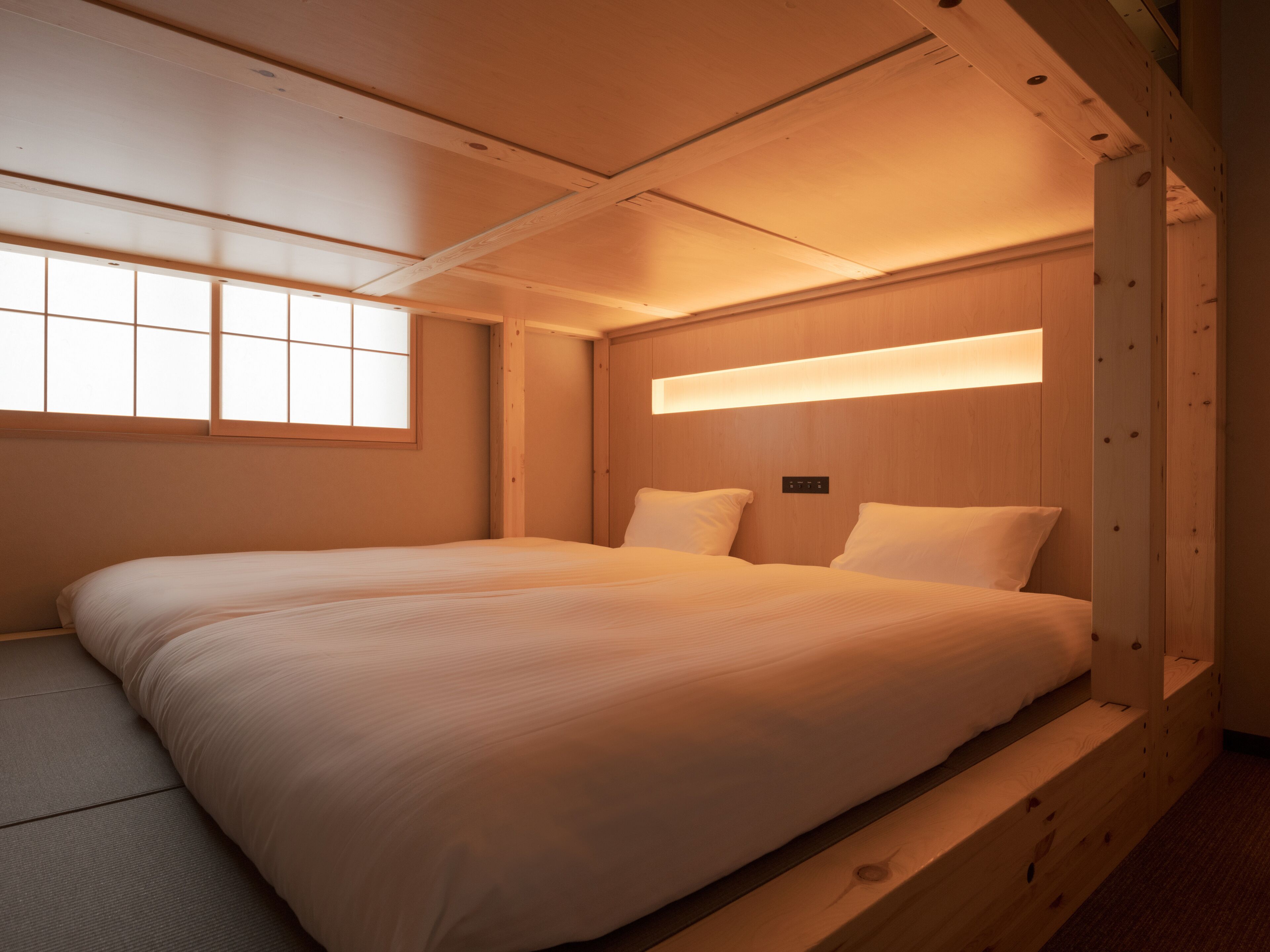 Une chambre avec un grand lit, une tête de lit en bois et une fenêtre donnant sur un beau paysage.