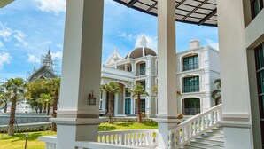 A grand hotel with a covered outdoor area, a staircase, and a view of a church with scaffolding. - Grand Lord Hotel& Residence (Sattahip)
