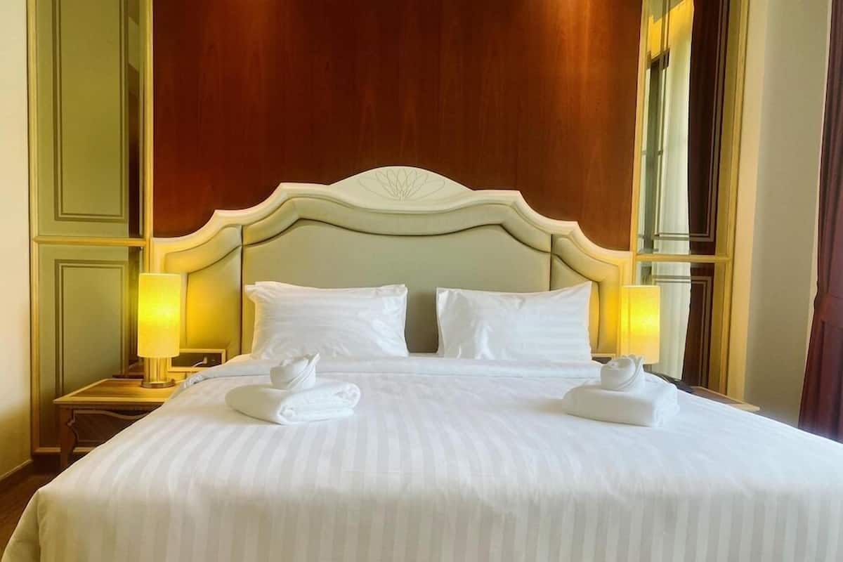 A hotel room with a large bed, two bedside lamps, and a wooden headboard.