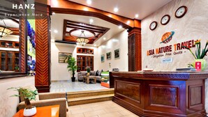 A hotel lobby with a reception desk, seating area, and a wall with clocks and a nature-themed sign. - HANZ LakeView Hotel Hanoi (Hanoi)