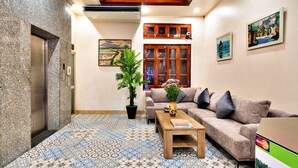 A living room with a patterned floor, a sofa, a coffee table, and a potted plant. - HANZ LakeView Hotel Hanoi (Hanoi)