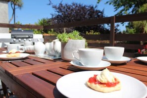Enjoy a meal al fresco in our garden patio, where a table is set with plates, cups, and a potted plant.