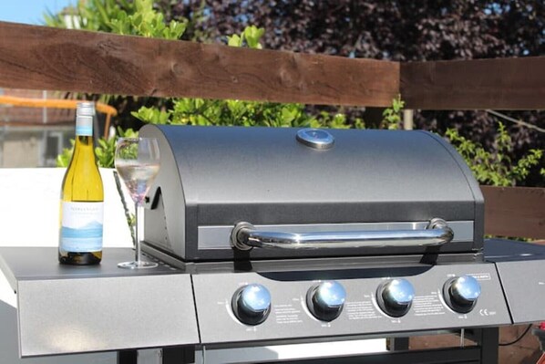 A stainless steel barbecue grill with a digital control panel and a bottle of white wine and a glass on the left.