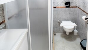Un baño con cabina de ducha, inodoro y lavamanos.