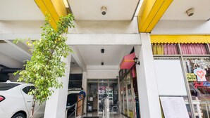 A building entrance with a yellow awning, a glass door, and a visible signboard. - OYO 893 Dian Suites Makati (Makati)