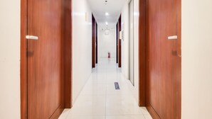A clean, modern hotel corridor with wooden doors and a tiled floor. - OYO 893 Dian Suites Makati (Makati)