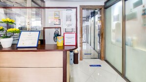 A reception desk with a framed certificate, a fan, and a potted plant. - OYO 893 Dian Suites Makati (Makati)