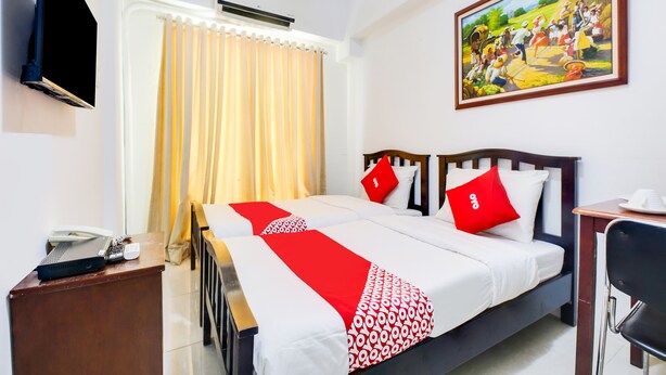 A hotel room with a bed, a desk, a telephone, an air conditioner, a television, and a painting on the wall. - OYO 893 Dian Suites Makati (Makati)