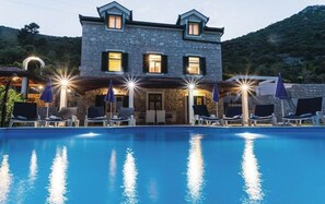 A stone building with a swimming pool, lounge chairs, and umbrellas. - Quiet Village Villa (Desne)