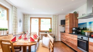 Eine moderne Küche mit Holzschränken, einem eingebauten Backofen und einem Essbereich mit Holztisch und -stühlen.