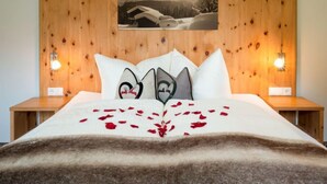 Ein Bett mit Holz-Kopfteil, weißen Kissen und einem Foto von Bergen.
