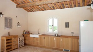 A kitchen with wooden cabinets, a white sink, and a window. - Villa in Provence with Infinity Pool (Apt)