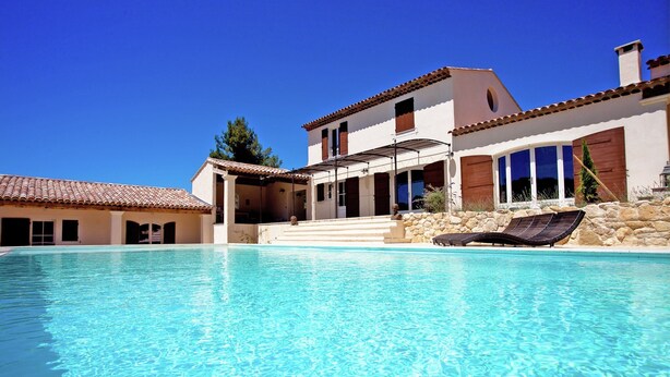 A swimming pool with a sun lounger, a covered patio, and a stone wall. - Villa in Provence with Infinity Pool (Apt)