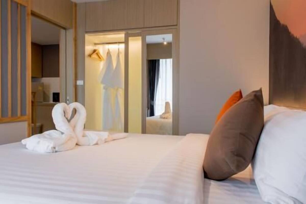 Una habitación de hotel con cama, espejo, armario y puerta que da a un baño.