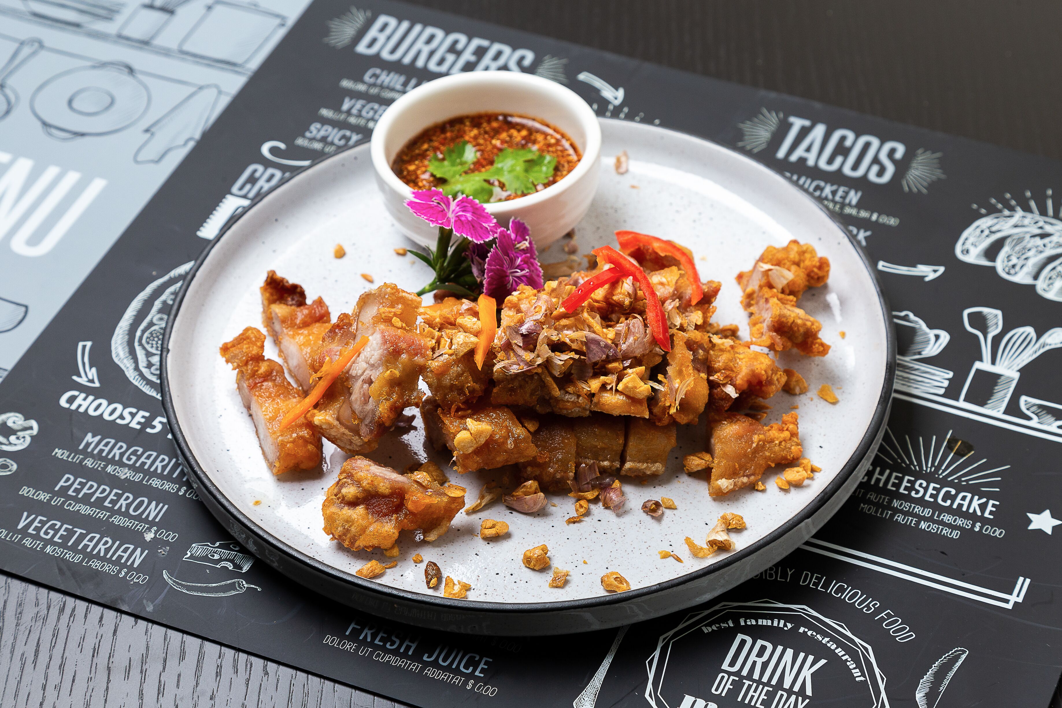 A plate of fried chicken with vegetables and a side of sauce, placed on a menu with various food options.