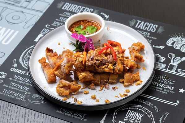 Un plato de pollo frito con verduras y una salsa, sobre un menú con diversas opciones de comida.