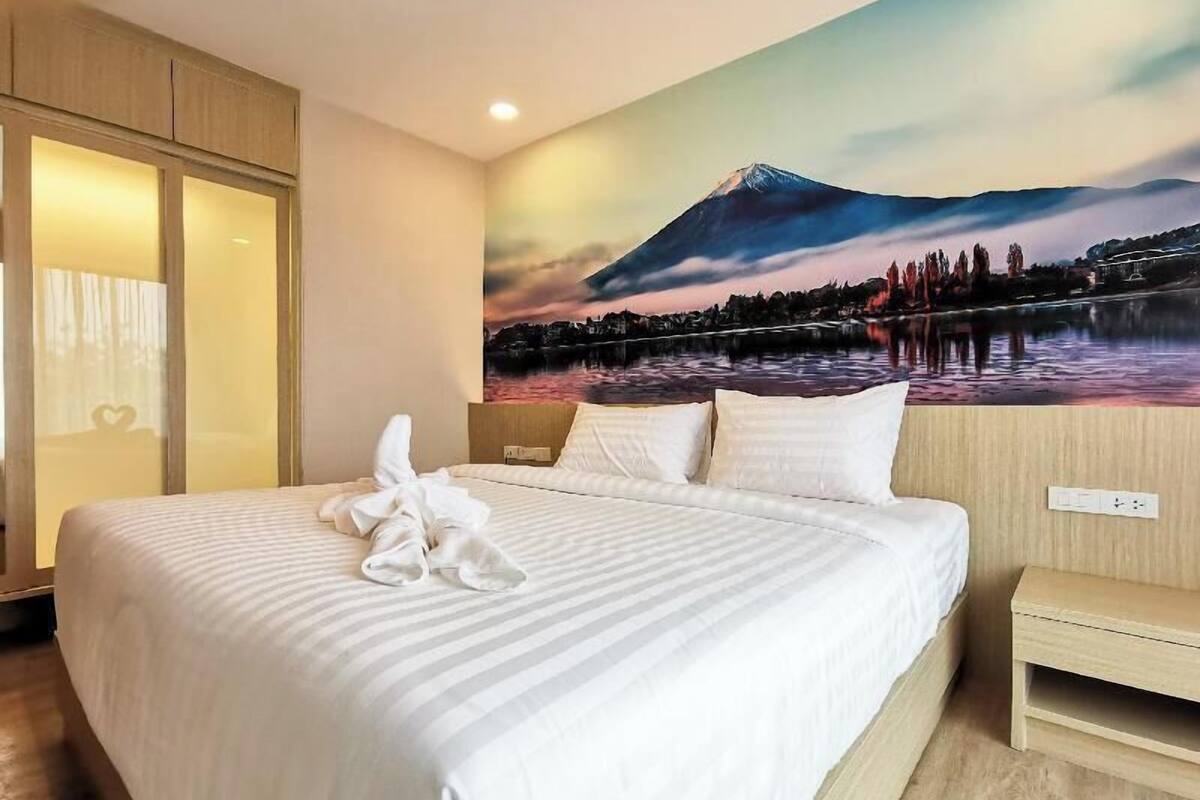 Habitación de hotel con cama, mesita de noche, un cuadro colgado en la pared de una montaña y un armario de madera.