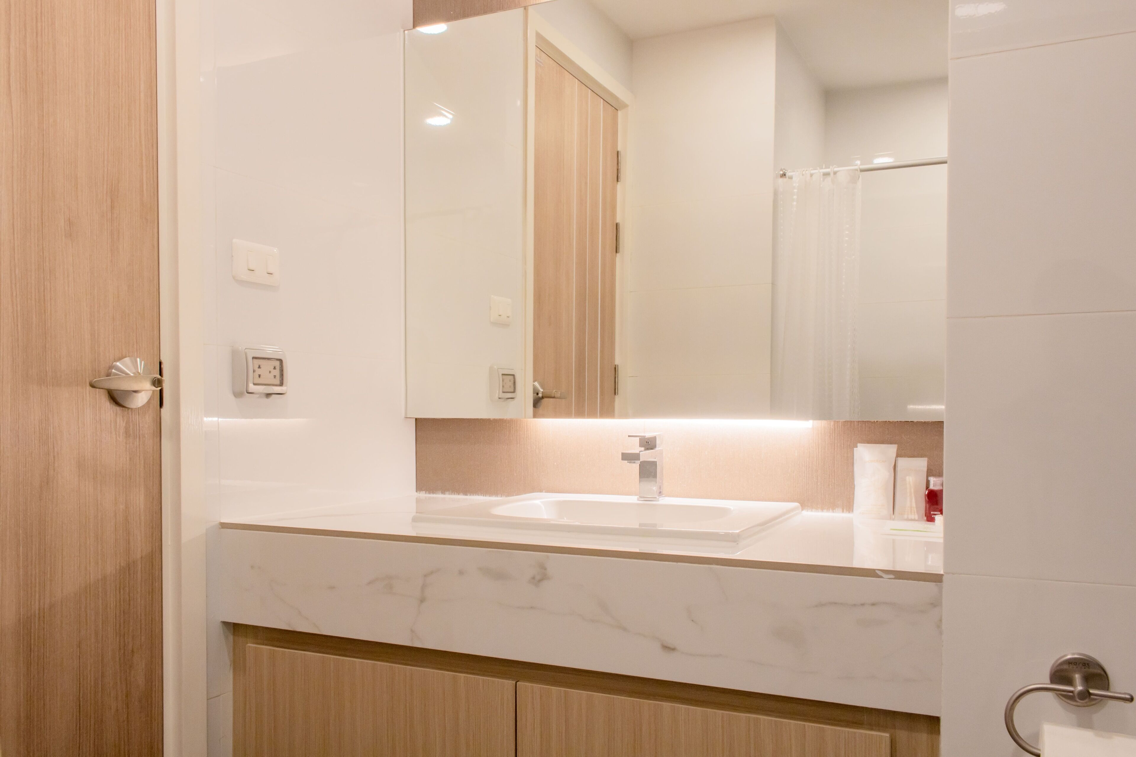 Un bagno moderno con lavabo in marmo, mobili in legno e uno specchio grande.
