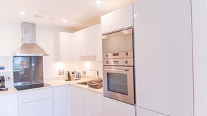 Una cocina moderna con armarios blancos, extractor de acero inoxidable, horno doble y lavavajillas integrado.