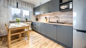 Une cuisine moderne avec des armoires grises, un plan de travail en bois, un four à micro-ondes encastré et une fenêtre donnant sur les arbres.