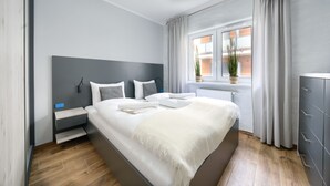 Une chambre moderne avec un grand lit, des murs gris et une fenêtre avec des rideaux.