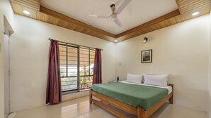Un dormitorio con cama de madera, ventilador de techo, ventana con cortinas e imagen enmarcada en la pared.