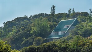 Una casa con techo pronunciado, rodeada de un bosque denso.