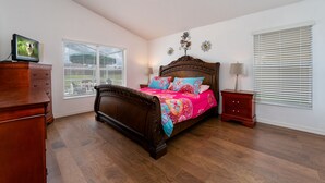 Un dormitorio con una cama de madera, dos mesitas de noche, un aparador y una ventana con persianas.