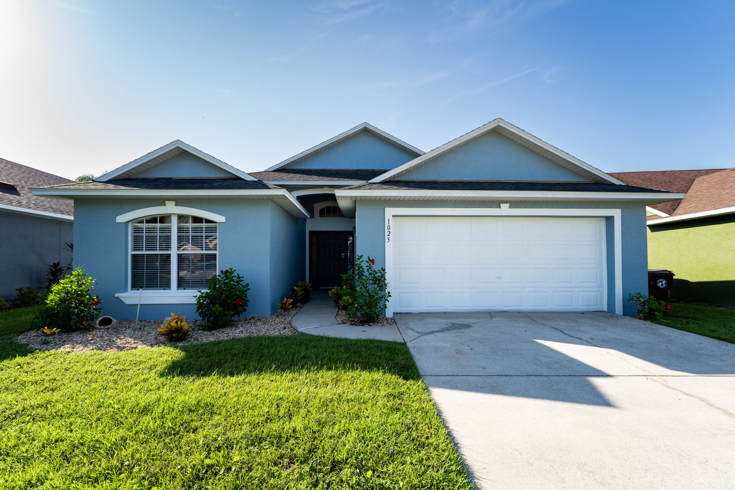 A two-story house with a garage, a well-maintained lawn, and a clear sky.