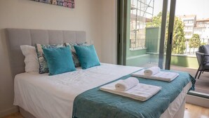 Une chambre à coucher avec un grand lit, deux oreillers, un plaid turquoise et deux serviettes enroulées.