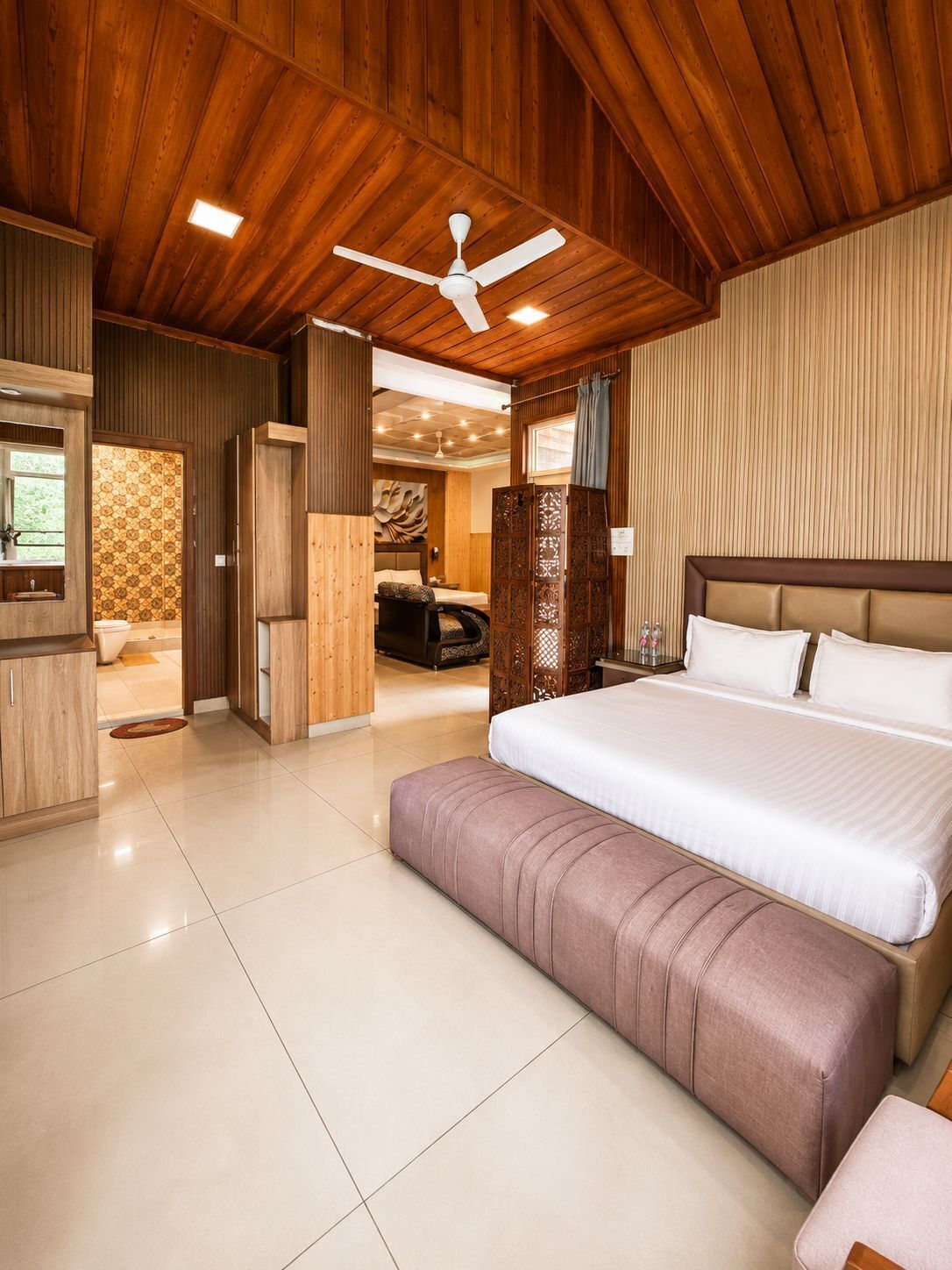 Un dormitorio amplio con una cama grande, un ventilador de techo y vistas al baño.