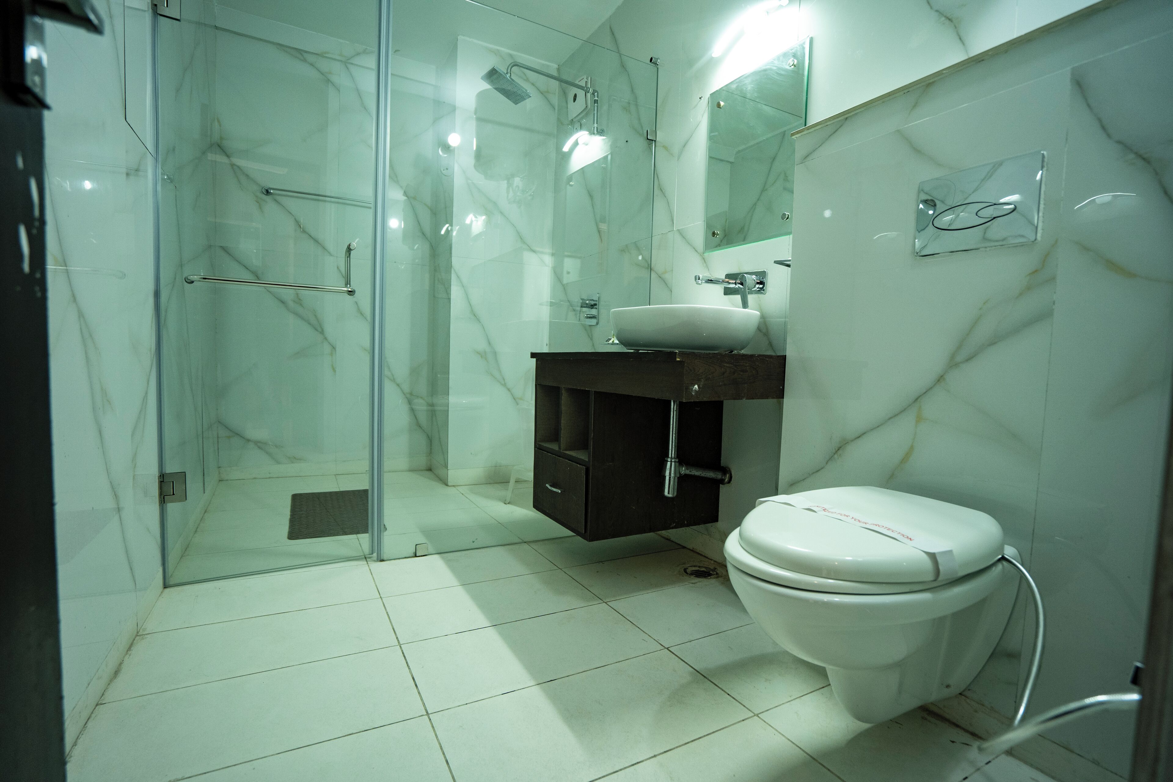 A modern bathroom with a glass-enclosed shower, a white sink, and a toilet.