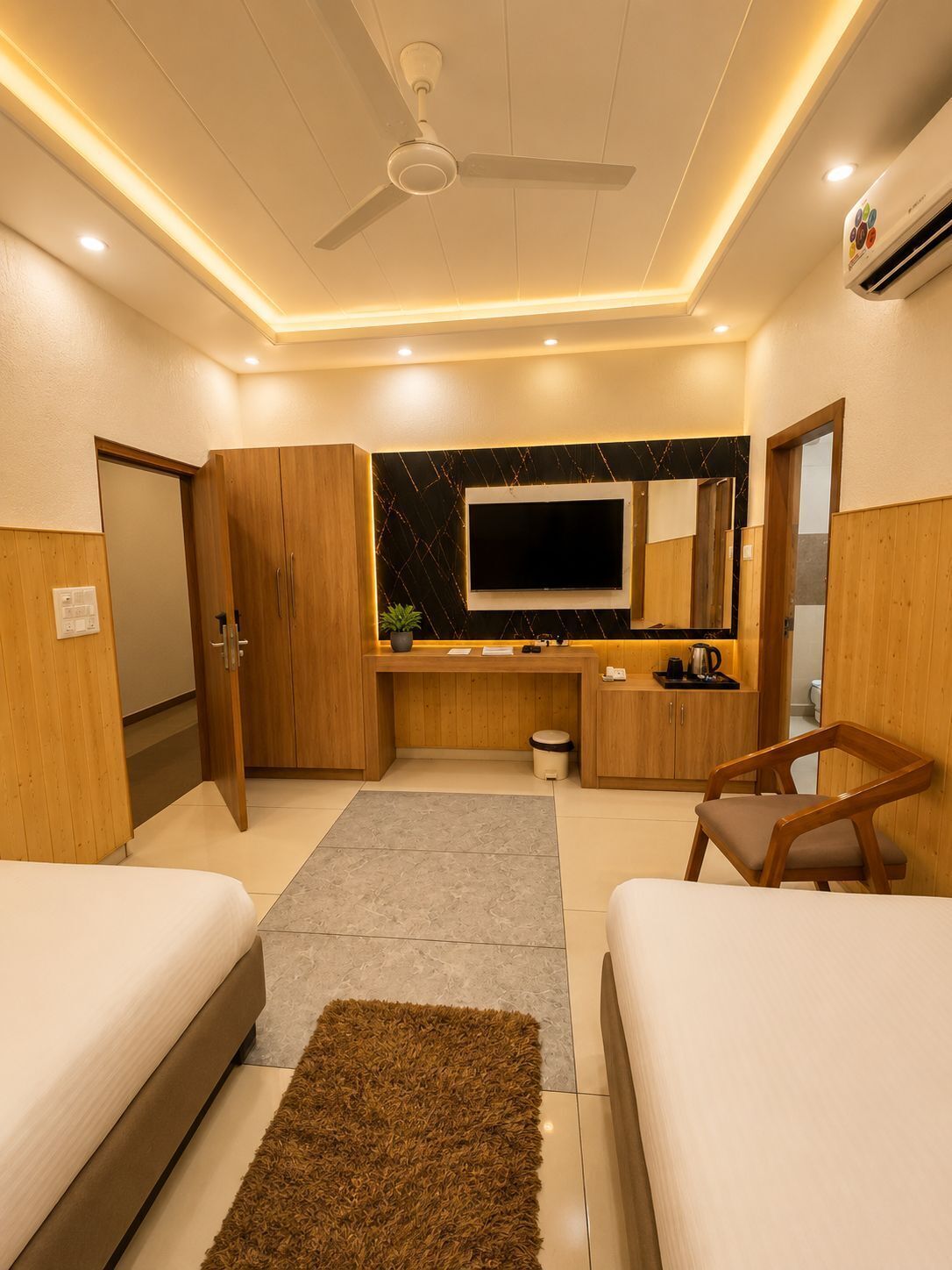 A modern hotel room with a bed, a desk, a chair, a TV, and a ceiling fan.