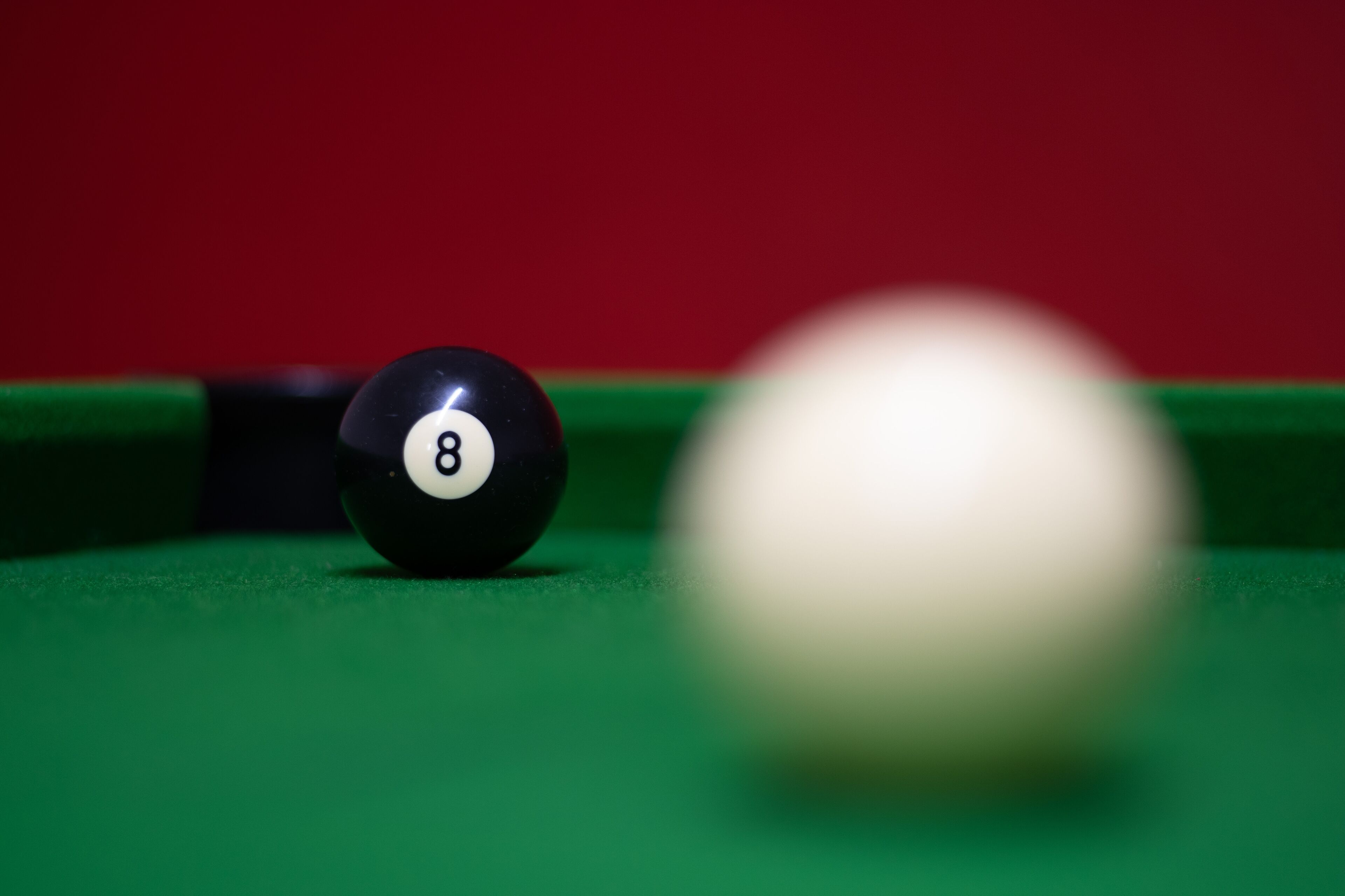 A close-up of a billiard ball marked with the number 8 on a green felt table.
