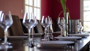 A dining table set with multiple wine glasses, plates, and a vase with a flower.