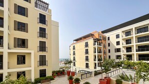 A multi-story residential building with balconies, potted plants, and a paved courtyard. - HiGuests - La Cote B2 (Dubai)