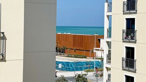 A view of a building with balconies overlooking a beach and a pool area. - HiGuests - La Cote B2 (Dubai)