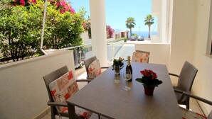 A balcony with a table set for two, featuring a bottle of wine and a potted plant. - Albania Dream Beachfront Apartment (Sarandë)