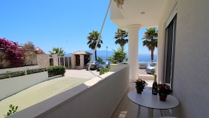 A balcony with a view of the sea, a table with potted plants, and a white chair. - Albania Dream Beachfront Apartment (Sarandë)