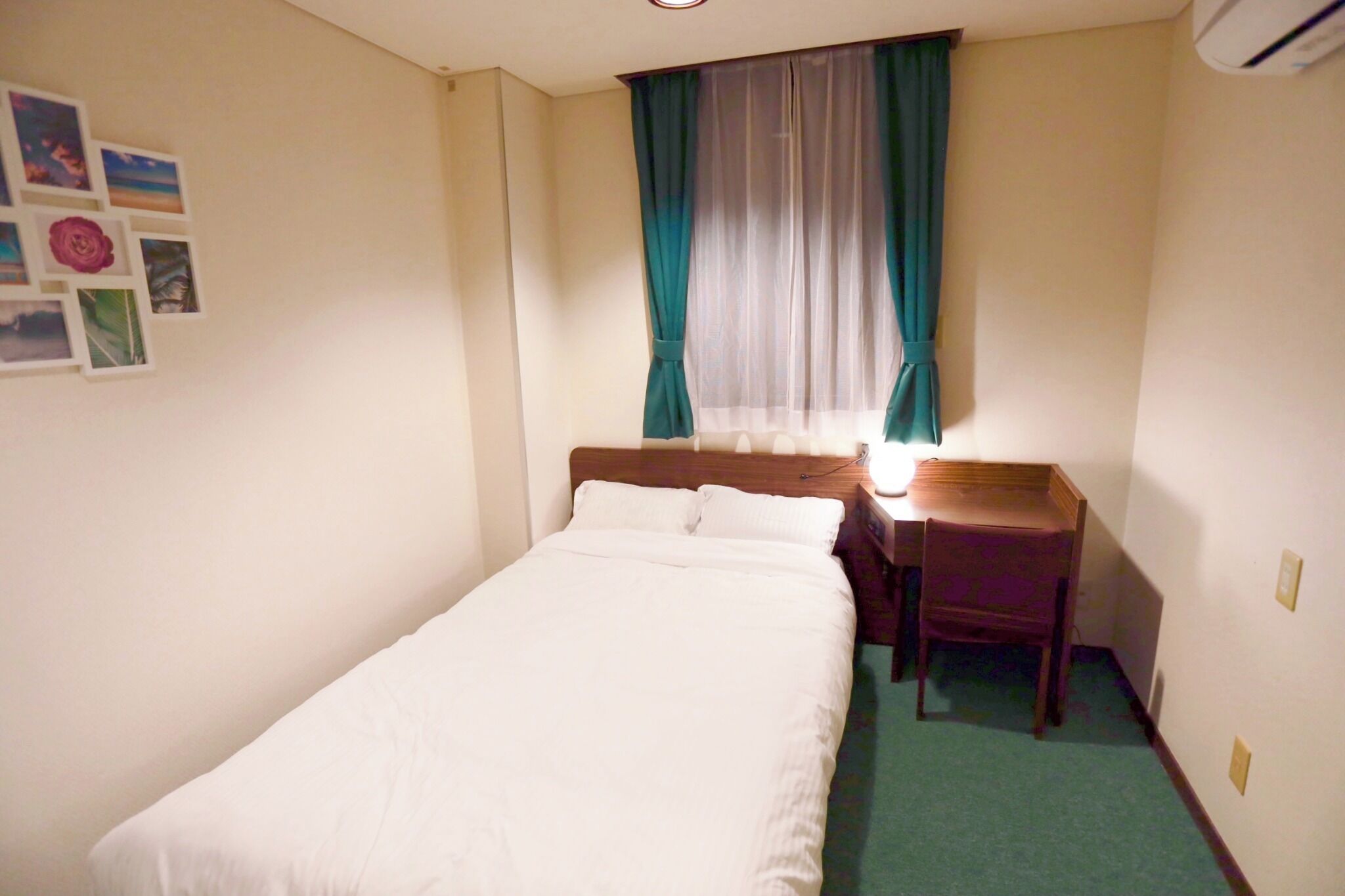Een compacte, verzorgde kamer met een enkel bed, een bureau en een stoel.